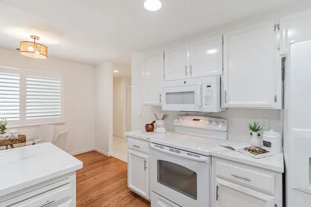 a kitchen with stainless steel appliances white cabinets a stove a sink and a window