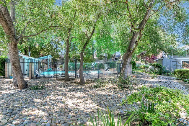 a backyard of a house with large trees and wooden fence