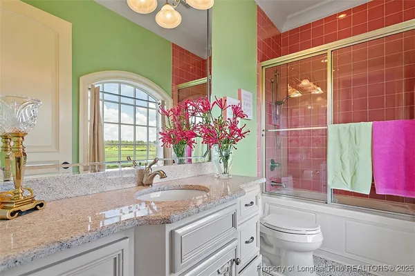 a bathroom with a granite countertop sink mirror vanity bathtub and next to a window