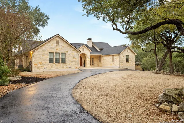 a front view of a house with a dirt yard and a large tree