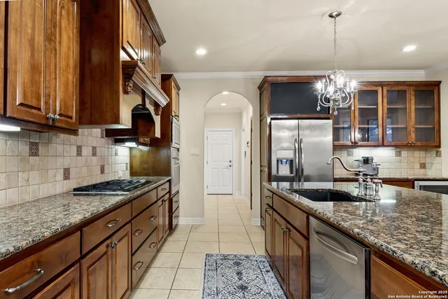a kitchen with granite countertop a sink a counter top space cabinets and stainless steel appliances