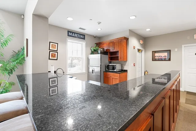 a large kitchen with kitchen island a large counter top stainless steel appliances and cabinets