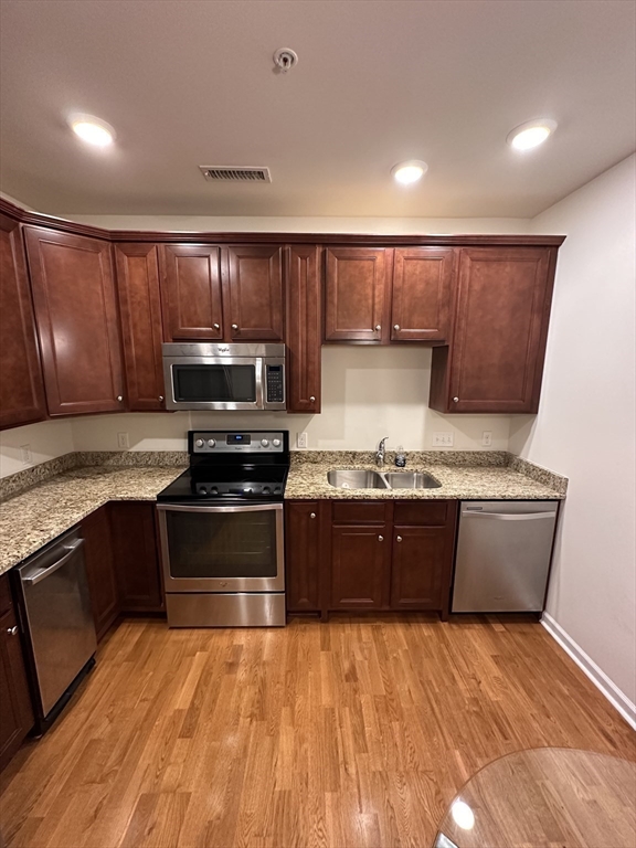 428 John Mahar Highway, Unit 301 Braintree, MA 02184 - Photo 8 of 41 a large kitchen with granite countertop wooden cabinets a stove and a granite counter top