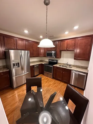 a kitchen with stainless steel appliances granite countertop a refrigerator a stove a sink dishwasher with a dining table and chair