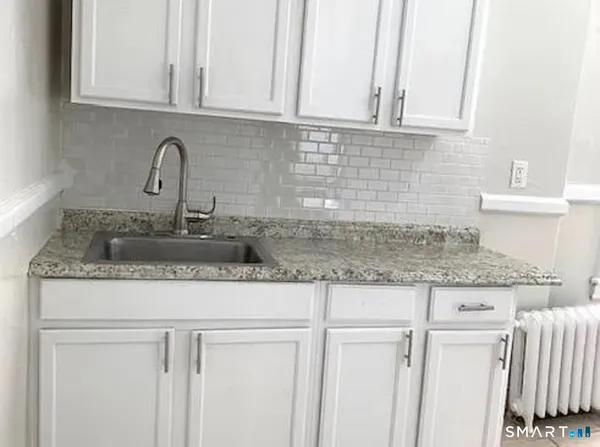 a kitchen with granite countertop white cabinets and a sink
