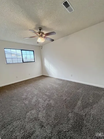 an empty room with windows and ceiling fan