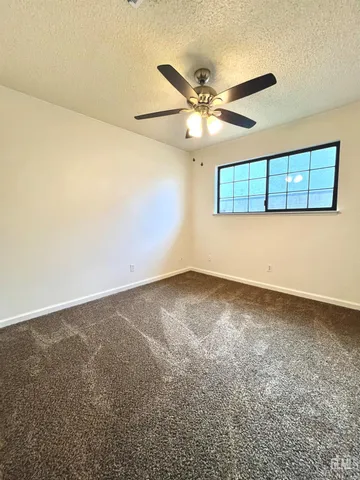 an empty room with a ceiling fan and a window