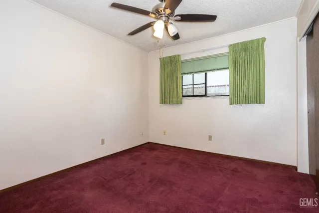 an empty room with a window and a ceiling fan