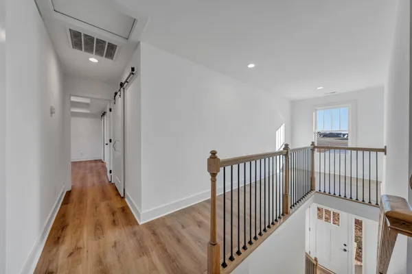 a view of a hallway with wooden floor and staircase