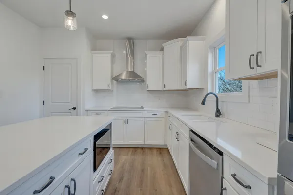 a kitchen with a sink dishwasher and white cabinets with wooden floor