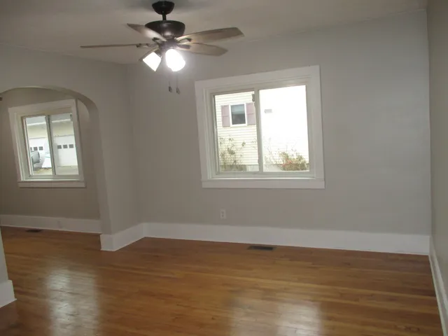 a view of an empty room with wooden floor and a window
