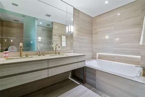 a bathroom with a double vanity sink a mirror and a bathtub