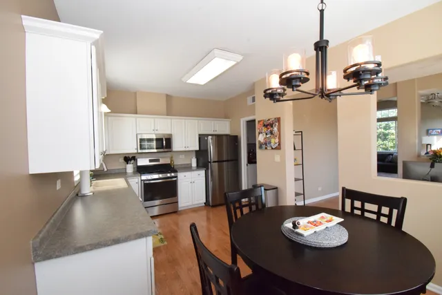 a kitchen with stainless steel appliances granite countertop a stove a kitchen island a dining table and chairs
