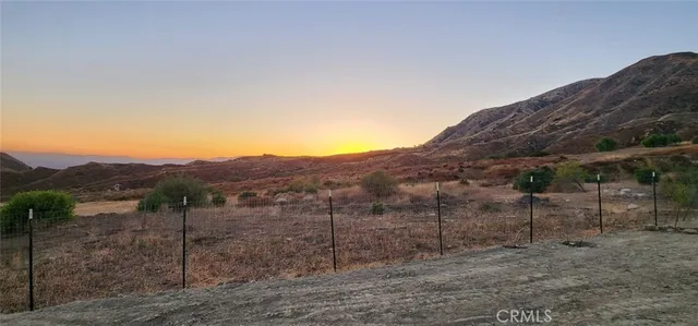a view of a dry field with mountains in the background
