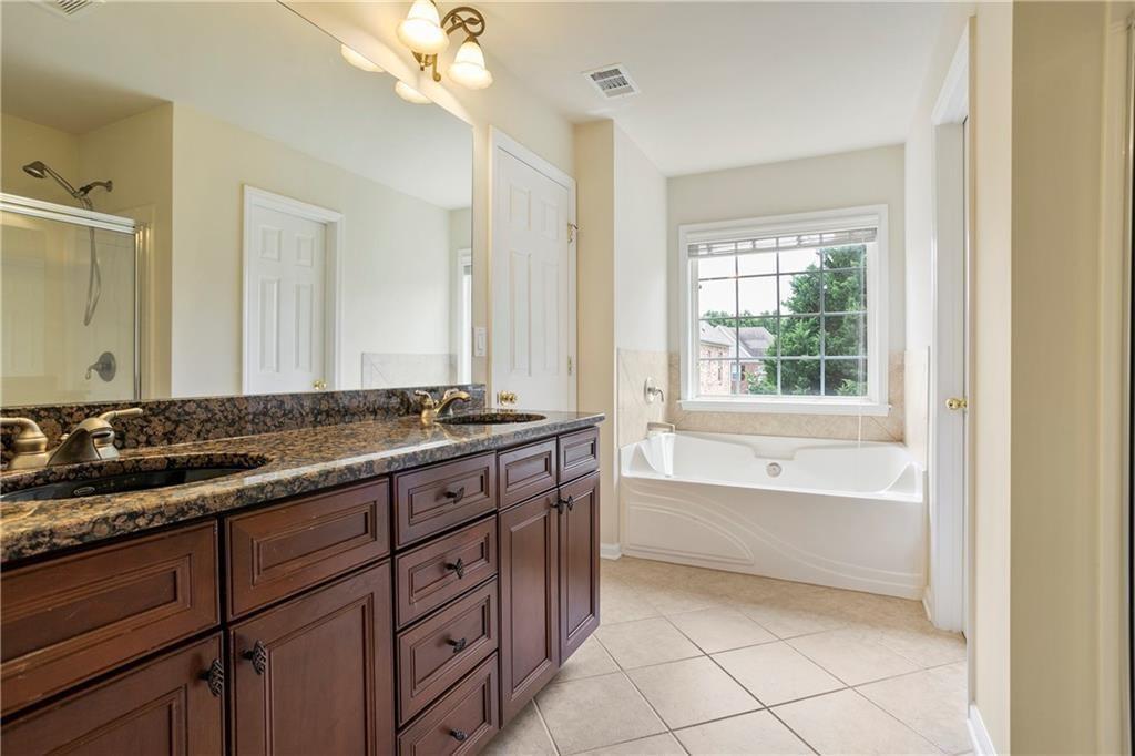 6108 Joybrook Road Johns Creek, GA 30097 - Photo 13 of 22 a bathroom with a granite countertop bathtub a sink and a large mirror