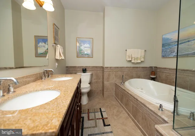 a bathroom with a granite countertop sink a toilet a mirror and bathtub
