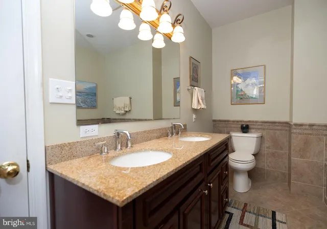 a bathroom with a granite countertop sink a toilet and a mirror