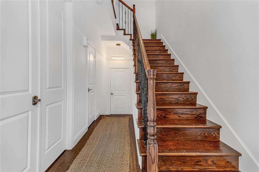 5744 Robbie Road Plano, TX 75024 - Photo 3 of 32 Hardwood staircase with wrought iron balusters and a dark wood handrail