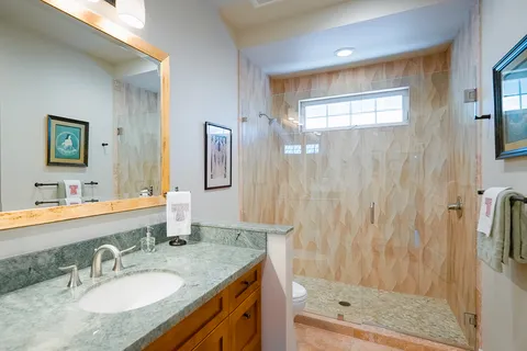 a bathroom with a granite countertop sink a mirror a bathtub and shower