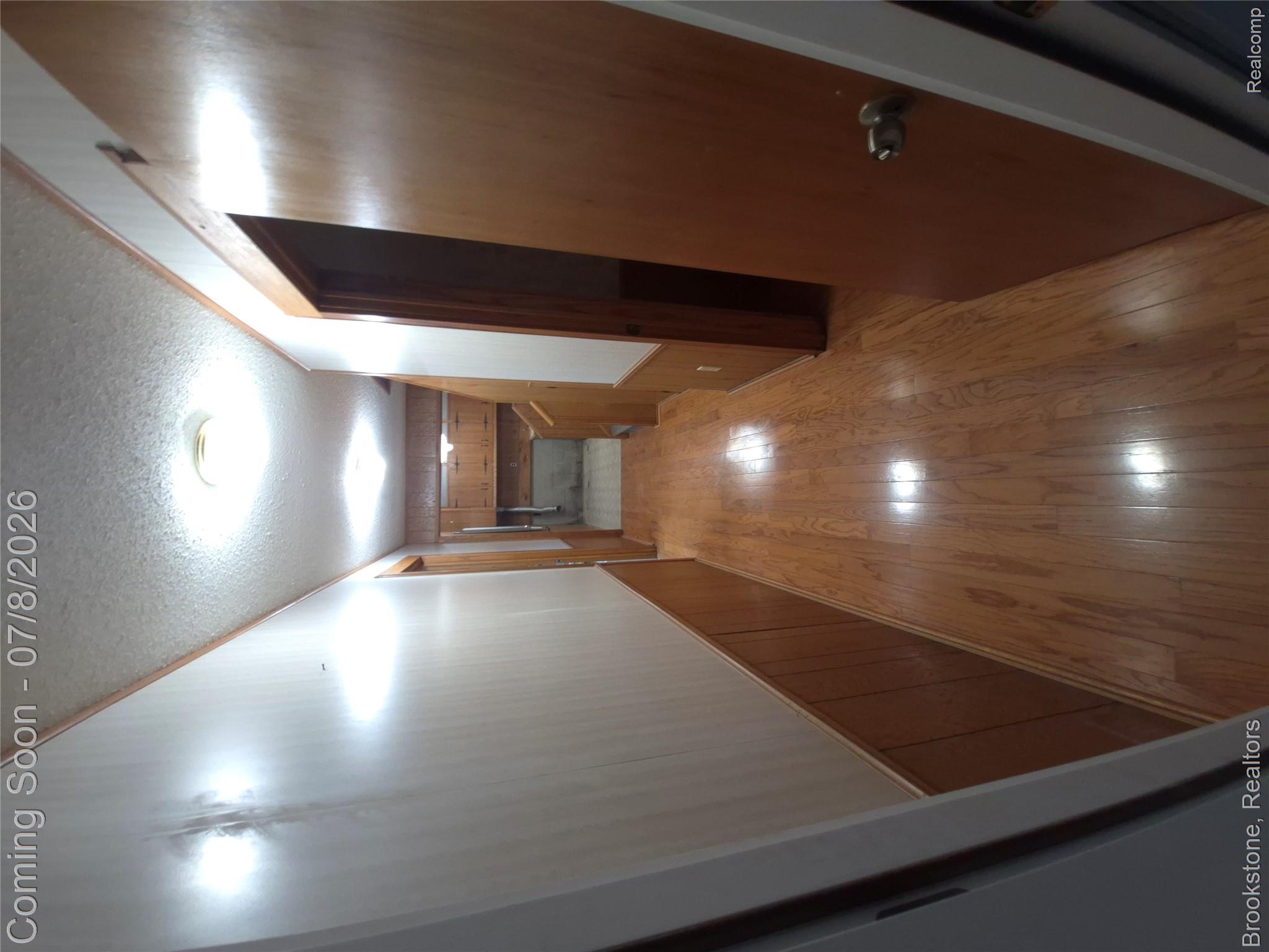 4140 South Henderson Road Davison, MI 48423 - Photo 72 of 98 Hallway featuring wood-finish flooring, wood paneling, and a textured ceiling