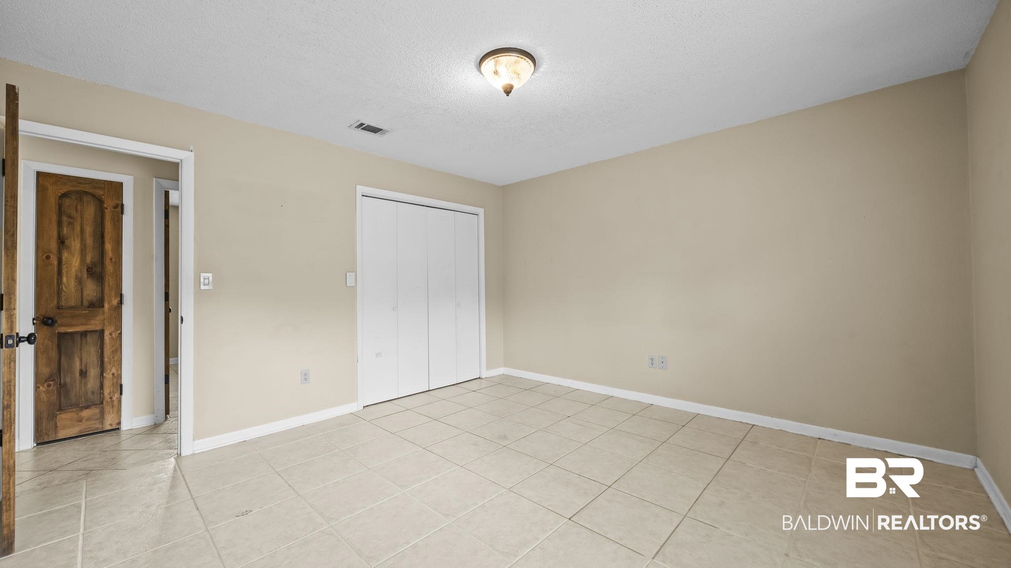 15096 Highland Circle Foley, AL 36535 - Photo 28 of 52 Spacious room featuring neutral wall paint, tile flooring, a bi-fold closet, and ceiling-mounted light fixture