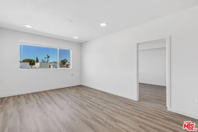 a view of an empty room with wooden floor and closet