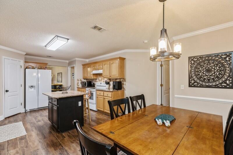 422 Swift Fox Run Crestview, FL 32536 - Photo 13 of 35 a view of a dining room with furniture a chandelier and wooden floor