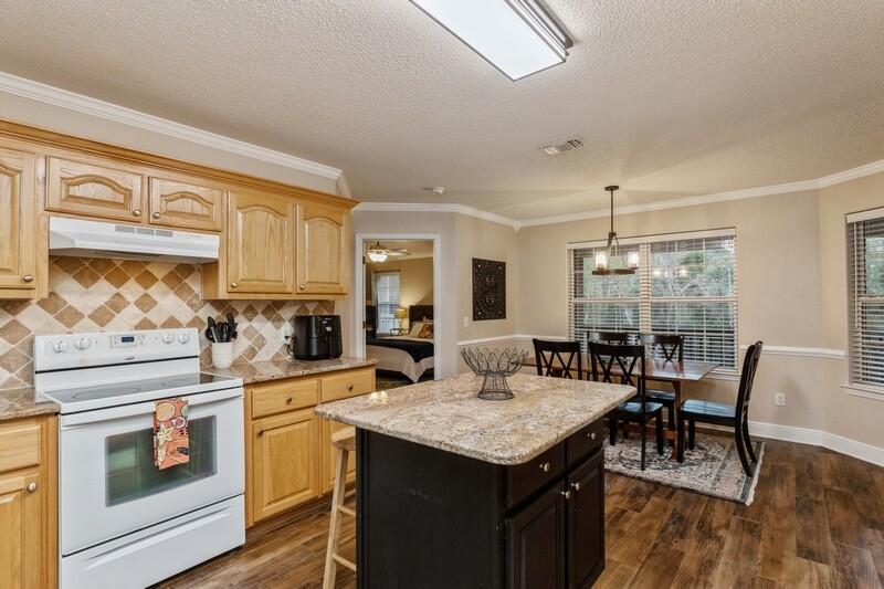 422 Swift Fox Run Crestview, FL 32536 - Photo 15 of 35 a kitchen with a stove a sink a kitchen island with chairs and wooden floor