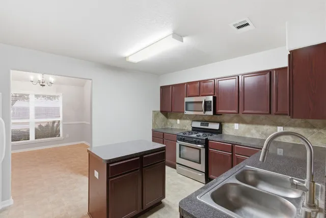 a kitchen with stainless steel appliances granite countertop a stove a sink and a microwave