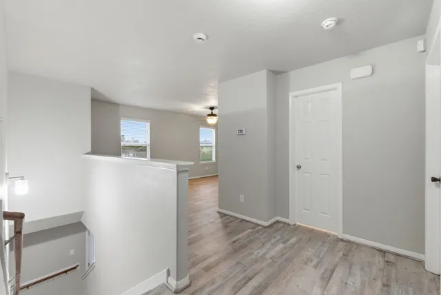 a view of an empty room with a window and wooden floor