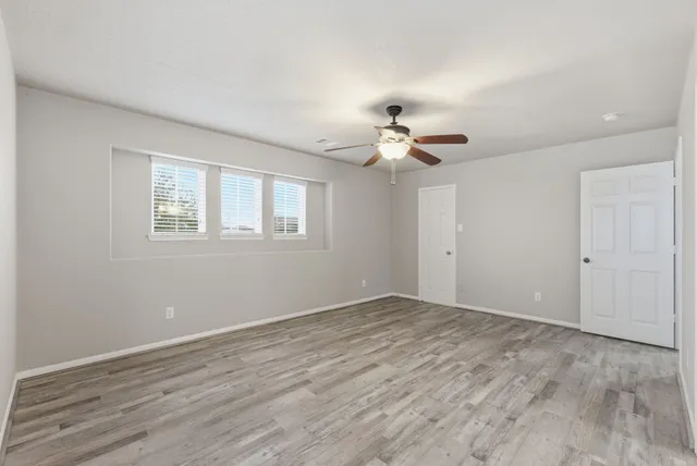 an empty room with wooden floor and windows