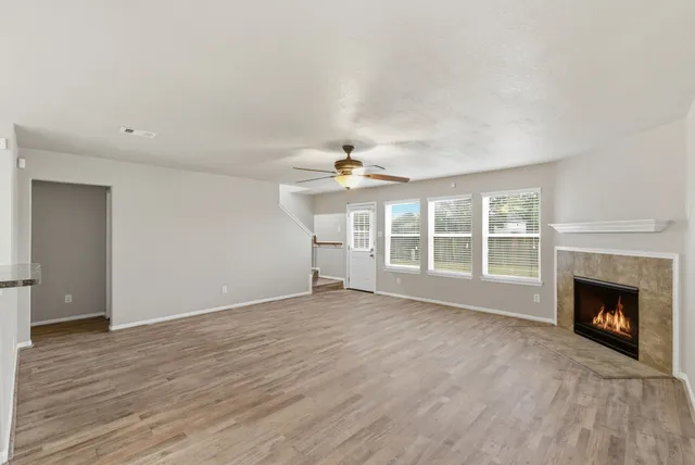 a view of an empty room with wooden floor fireplace and a window
