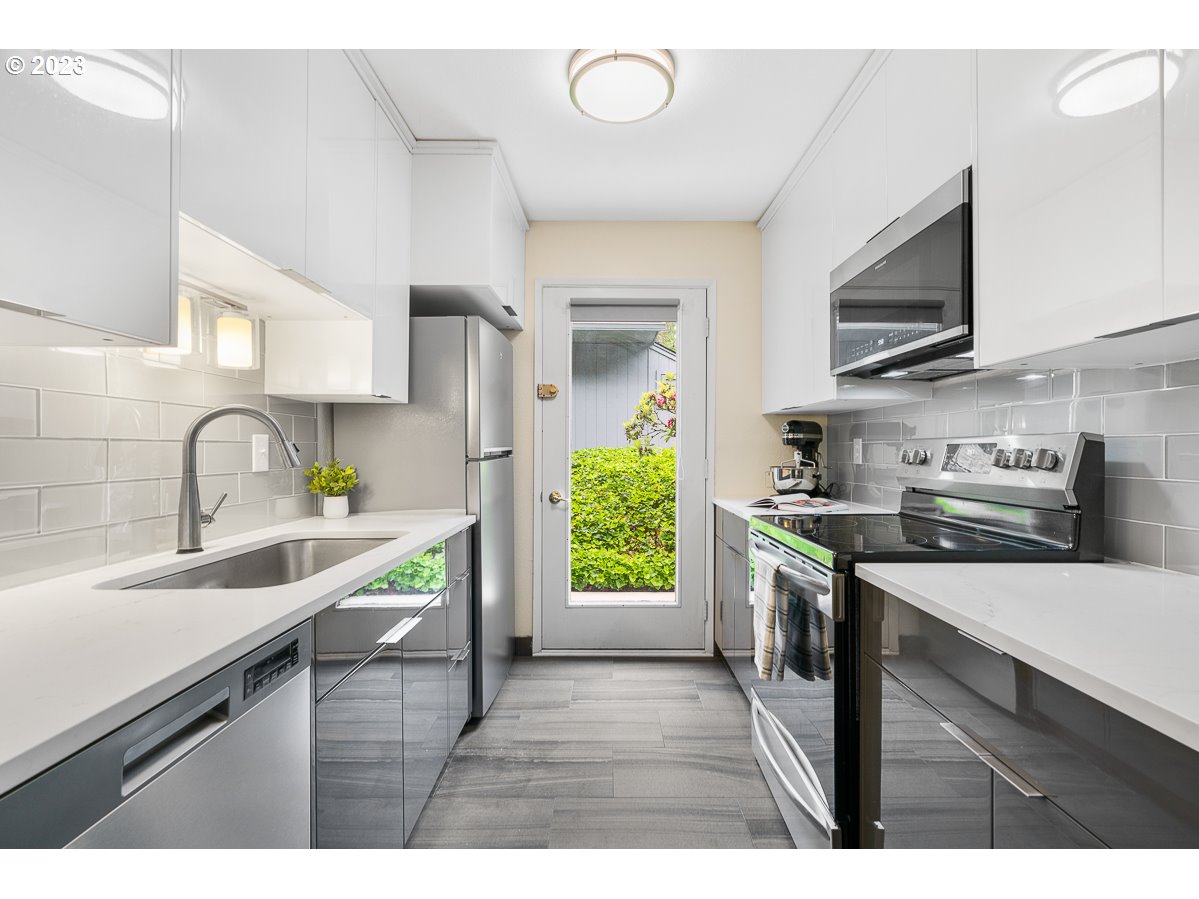 4308 Southwest Dickinson Street, Unit 15 Portland, OR 97219 - Photo 10 of 35 a kitchen with stainless steel appliances a sink stove and cabinets