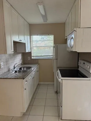 a kitchen with granite countertop a sink a stove and cabinets