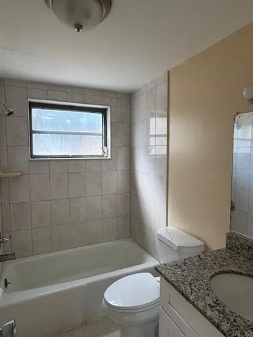 a bathroom with a granite countertop toilet a sink and bathtub