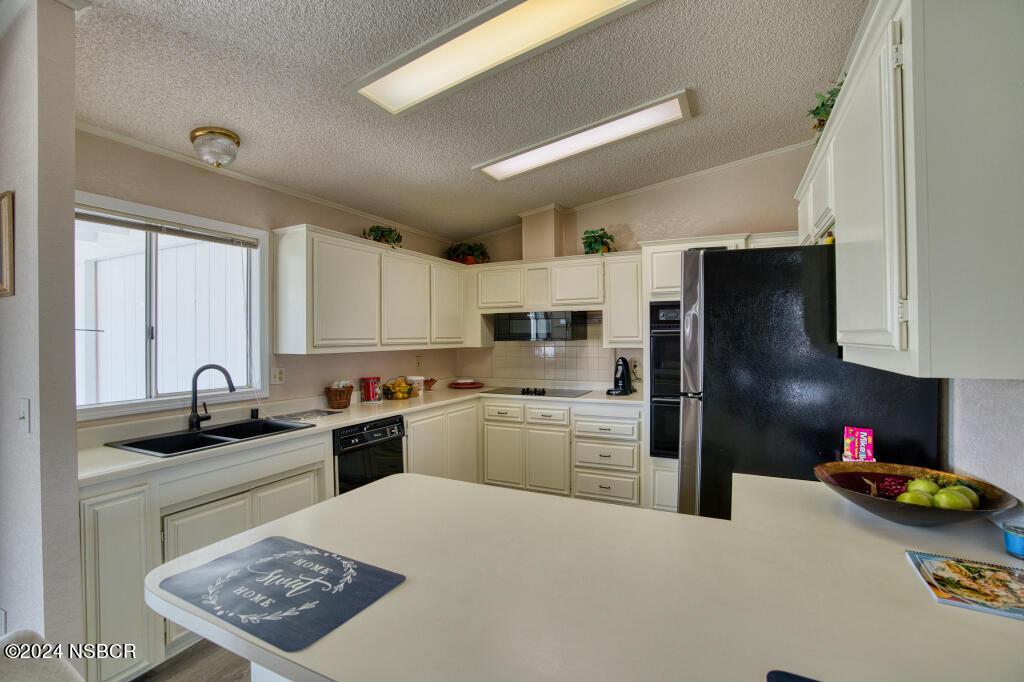 919 Vista Del Rio Santa Maria, CA 93458 - Photo 4 of 29 a kitchen with a sink dishwasher a refrigerator a stove and white cabinets with wooden floor