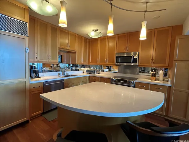 a kitchen with stainless steel appliances kitchen island granite countertop a sink a stove a refrigerator cabinets and chairs