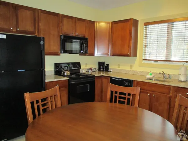 a kitchen with stainless steel appliances a stove a sink a microwave a refrigerator a stove a dining table and chairs