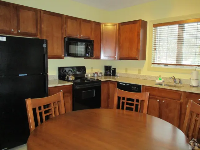 a kitchen with stainless steel appliances a stove a sink a microwave a refrigerator a stove a dining table and chairs