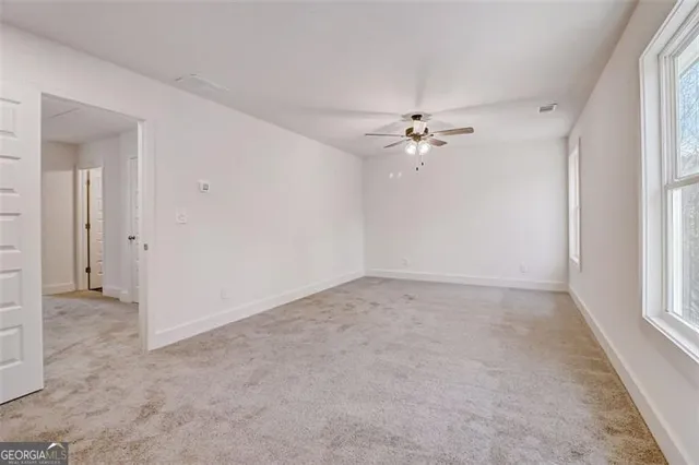 an empty room with fan and windows