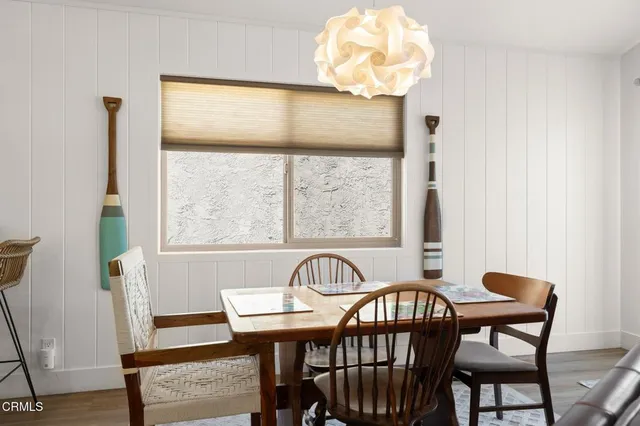 a kitchen with stainless steel appliances granite countertop a stove top oven a refrigerator a dining table and chairs with wooden floor