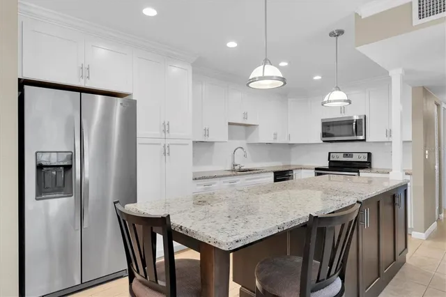 a kitchen with stainless steel appliances granite countertop a refrigerator a sink and a stove