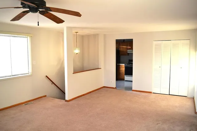 an empty room with closet and a chandelier fan