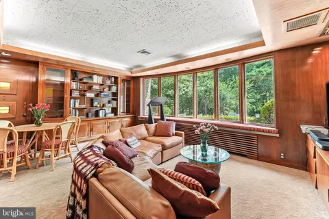 a view of a dining room with furniture a chandelier and large windows