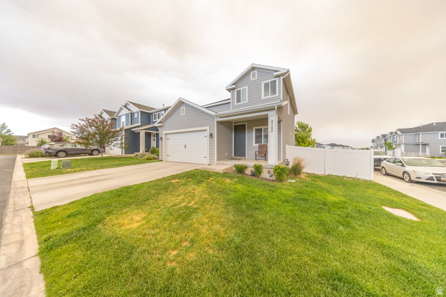 4765 Breezy Patch Road Eagle Mountain, UT 84005 - Photo 2 of 25 Two-story residence featuring light gray siding, a white garage door, and a covered porch entry