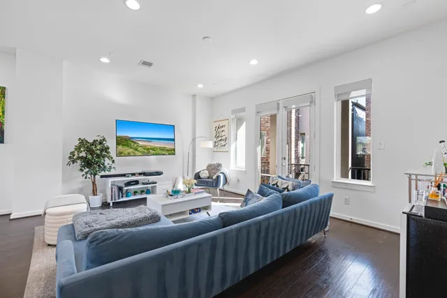 a room with stainless steel appliances kitchen island granite countertop a refrigerator a sink dishwasher a dining table and chairs with wooden floor