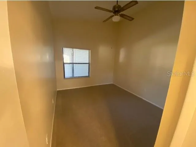 an empty room with a window and a ceiling fan