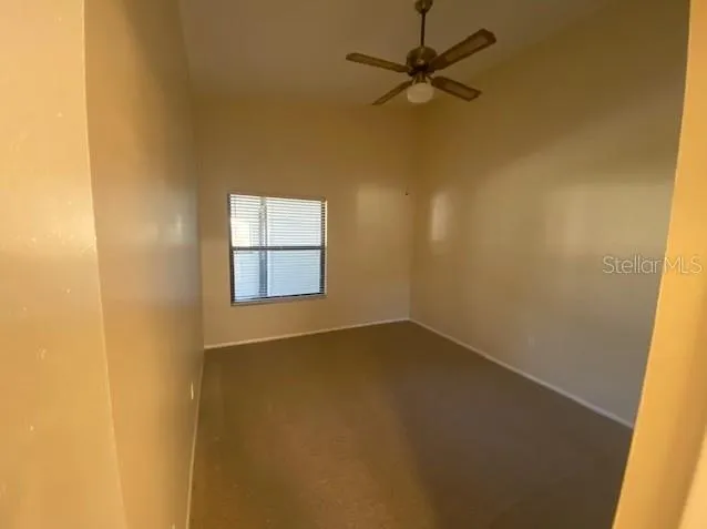 an empty room with a window and a ceiling fan