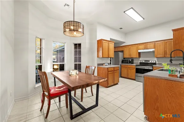 a kitchen with a dining table chairs and refrigerator