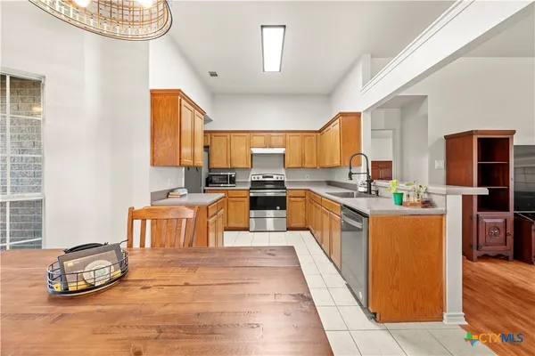 a large kitchen with stainless steel appliances granite countertop a stove a sink dishwasher and a microwave oven with cabinets